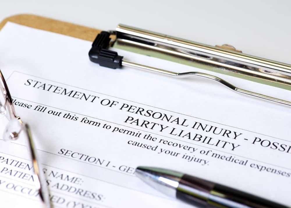 Personal injury claim on clipboard with pen and glasses.