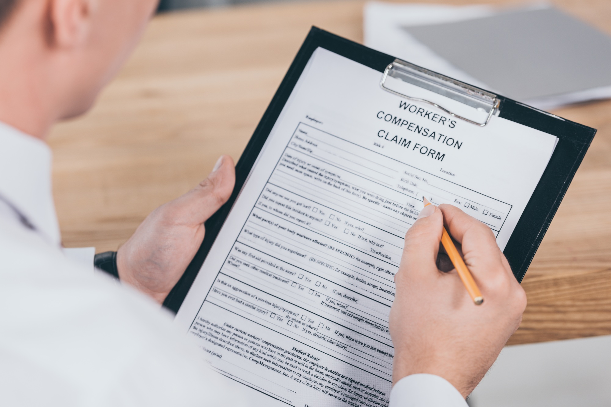 cropped view of businessman filling in compensation claim form at the office