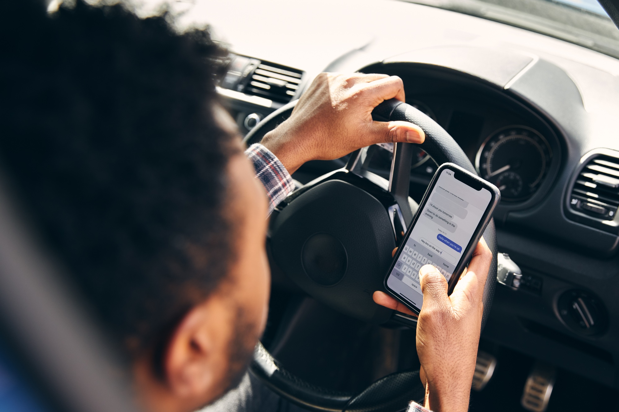 Dangerous Driving From Man Texting On Mobile Phone With One Hand On Steering Wheel