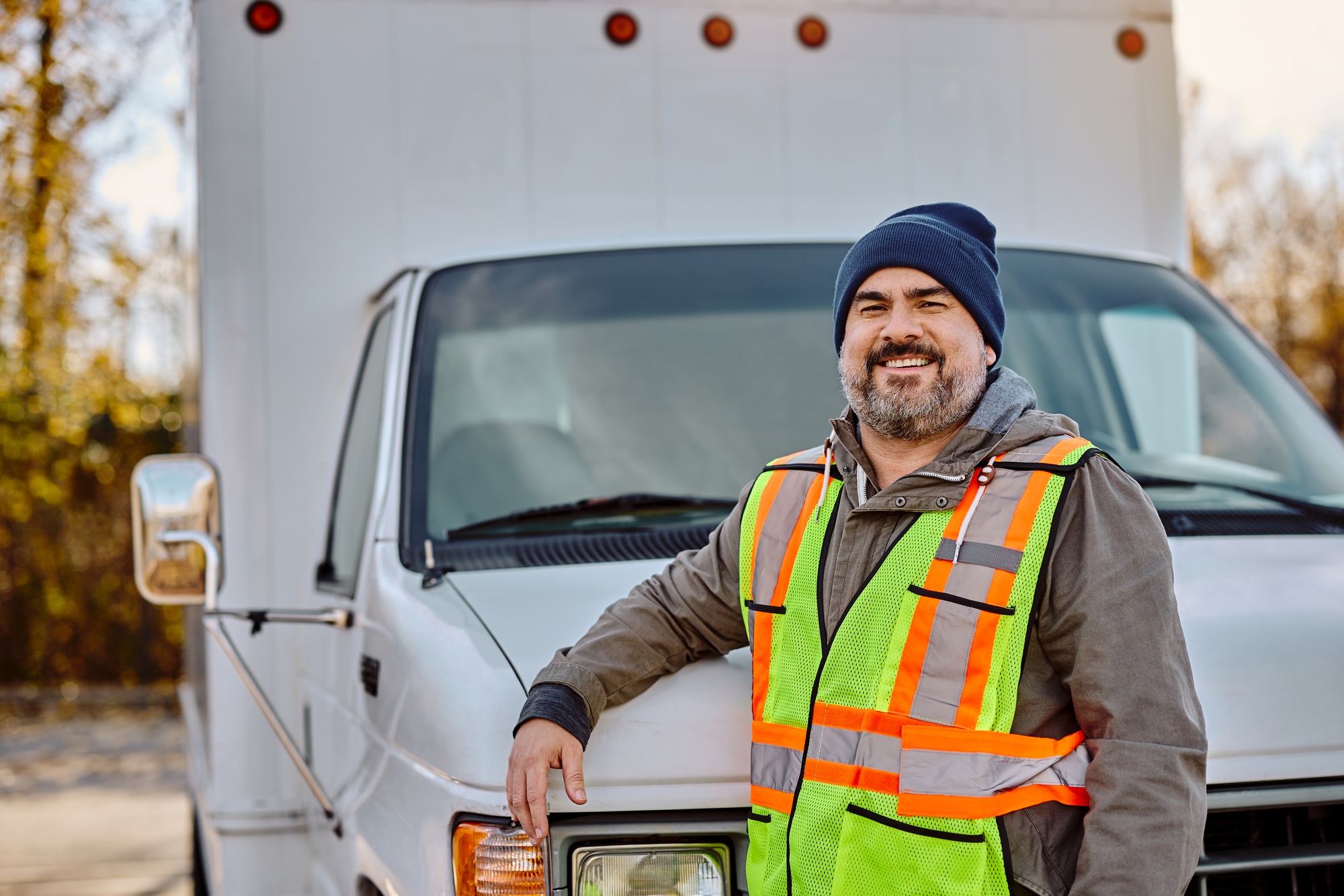 Happy driver in front of his truck looking at camera.