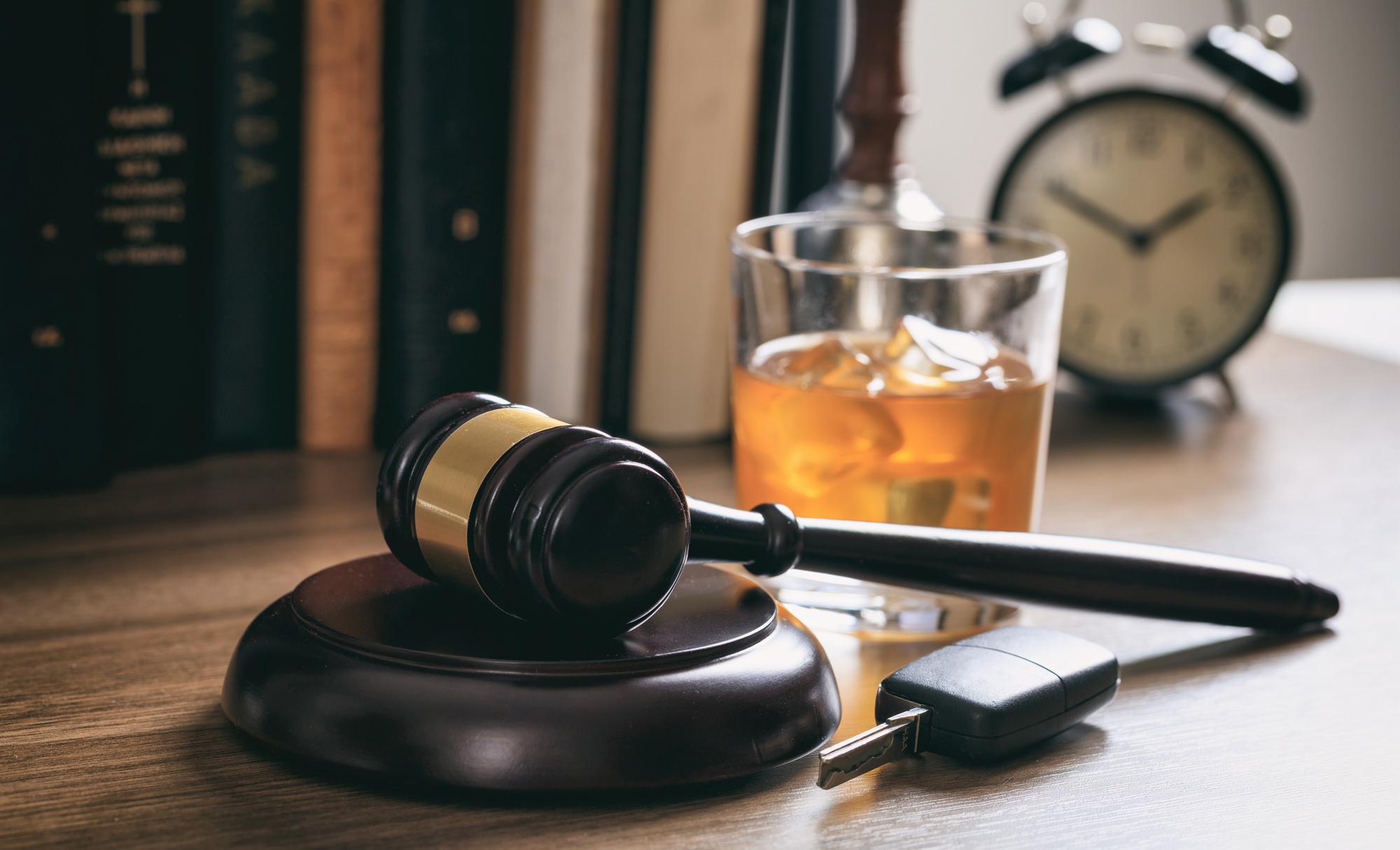 Law gavel, alcohol and car keys on a wooden desk, dark background