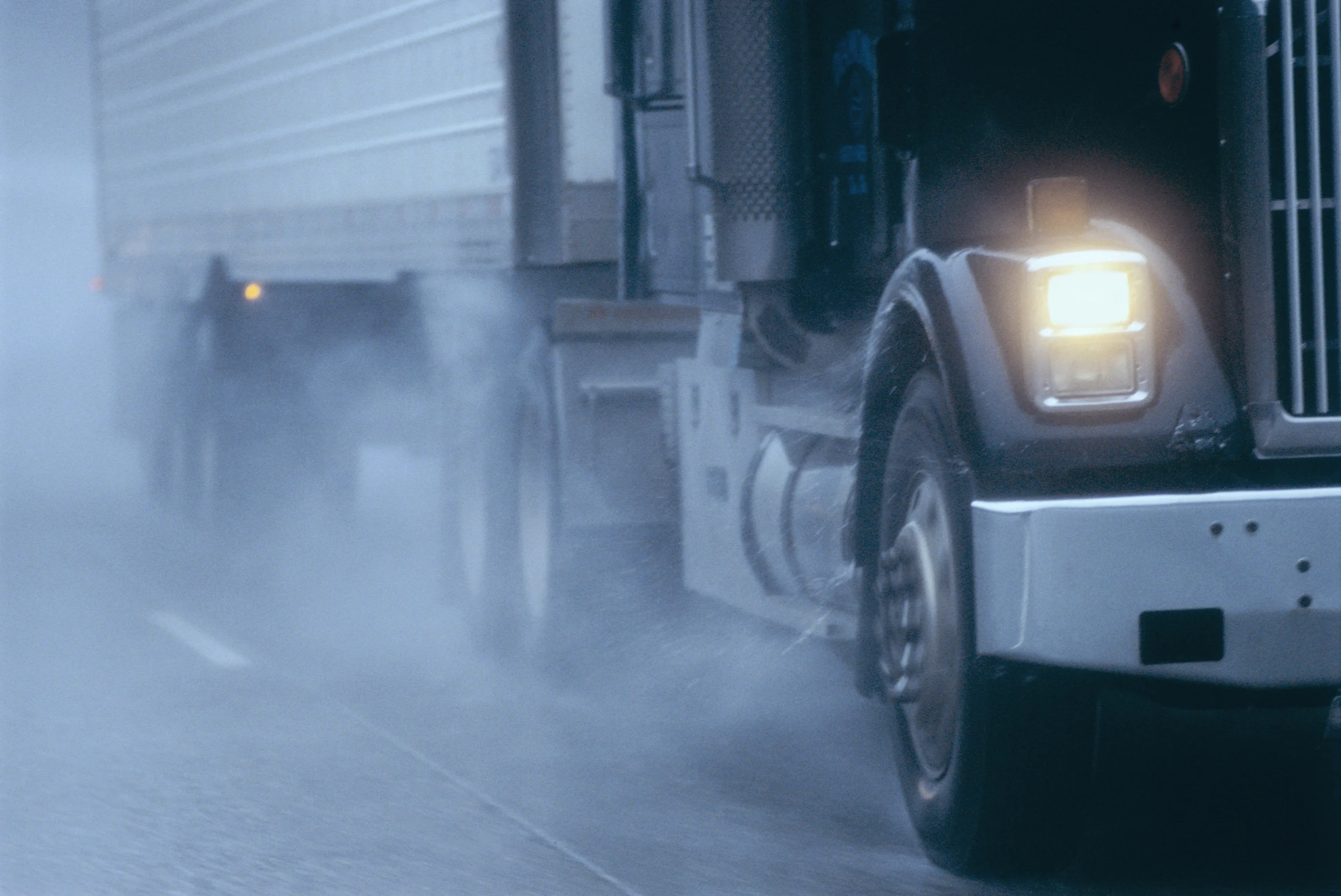 partial view of large commercial truck driving in rainy conditions